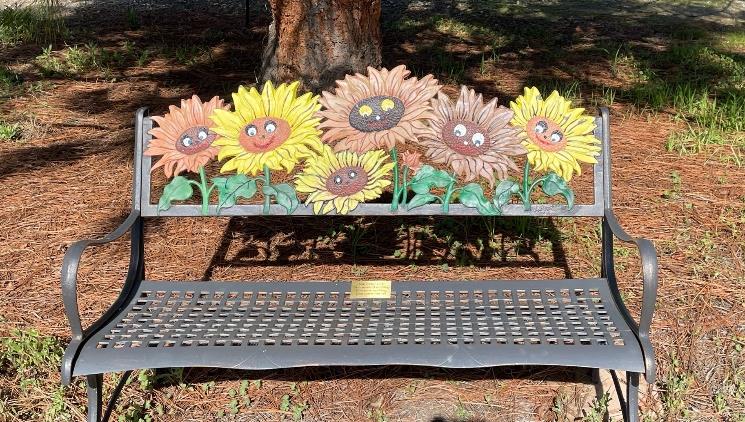 Bench plaque to honor Valerie Lee, with smiling sunflowers as decoration.